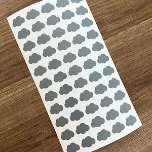 May include: A sheet of grey cloud stickers on a white background. The clouds are arranged in a repeating pattern.