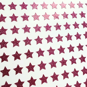 May include: A sheet of pink glitter star stickers. The stars are arranged in rows, with each row slightly offset from the one above it. The stars are all the same size and shape.