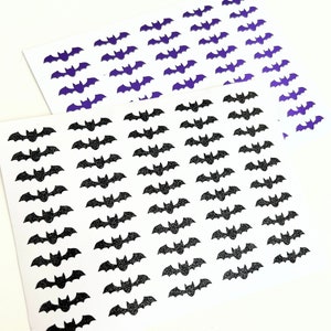 May include: Two sheets of white paper with black and purple glitter bats printed on them. The bats are arranged in rows and columns.