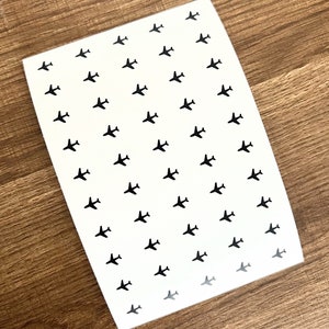 May include: A sheet of white paper with a repeating pattern of black airplane silhouettes.