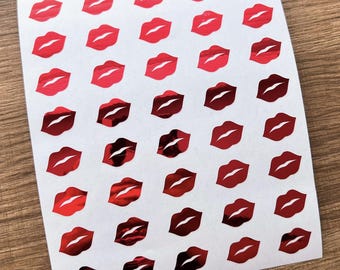 Könnte beinhalten: Blatt mit Aufklebern mit einem Muster roter Lippen. Die Lippen haben eine glänzende, reflektierende Oberfläche, die ein lebendiges und auffälliges Design erzeugt. Die Aufkleber sind in einem Raster auf weißem Hintergrund angeordnet.