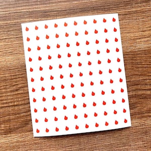 May include: A rectangular white sheet featuring a repeating grid pattern of small, vibrant red flame icons. The icons are arranged in uniform rows and columns across the entire surface of the paper, creating a consistent and repetitive graphic design.