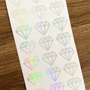 May include: A sheet of iridescent diamond stickers. The stickers are white with a holographic finish that shifts colours in the light. There are 20 stickers on the sheet.