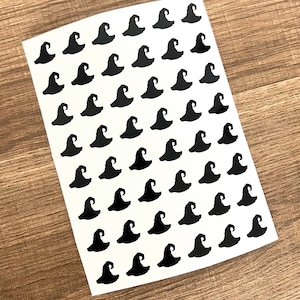 May include: A sheet of white paper with 49 black witch hat stickers. The stickers are arranged in a grid pattern.