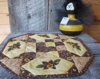 A Very Cute Quilted  Hexagon Table Topper In Shades Of Brown, Tan and Yellow Covered With Sunflowers and Honey Bees