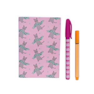 May include: A pink notebook featuring a pattern of gray cats with banners saying "You are so loved." Beside it are a pink patterned pen and an orange pen.