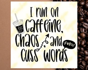 May include: Black and white graphic design featuring a coffee cup and the text "I run on caffeine, chaos and cuss words". The text is in a speech bubble with an exclamation mark. The graphic is set against a brown background with coffee beans.