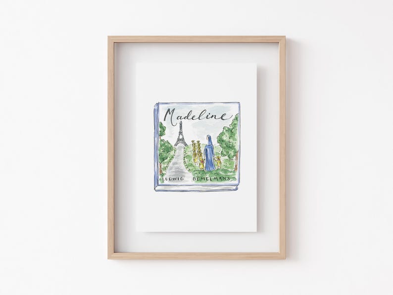May include: A framed print of the book "Madeline" by Ludwig Bemelmans. The watercolor illustration on the cover depicts the Eiffel Tower, a path, and figures in blue and yellow. The title "Madeline" is written in cursive.