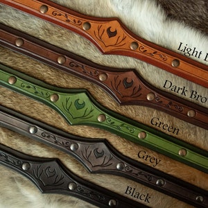 May include: Five leather belts with different colored leather and metal accents. The belts have a decorative design with a crescent moon and antlers. The colors are light brown, dark brown, green, grey, and black.