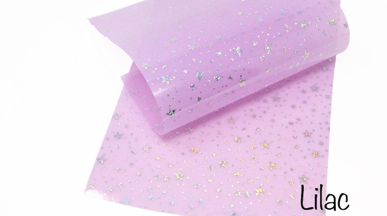 Pu&ograve; includere: Tessuto trasparente color lilla con motivo a stelle iridescenti.