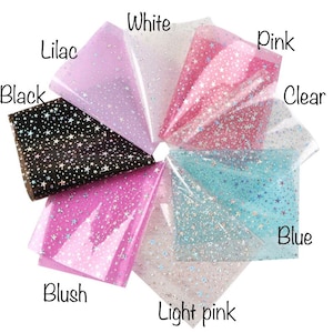 Pu&ograve; includere: Un assortimento di otto fogli di vinile trasparente con un motivo a stelle olografiche. I fogli sono di colore nero, lilla, bianco, rosa, rosa chiaro, blush, blu e trasparente.