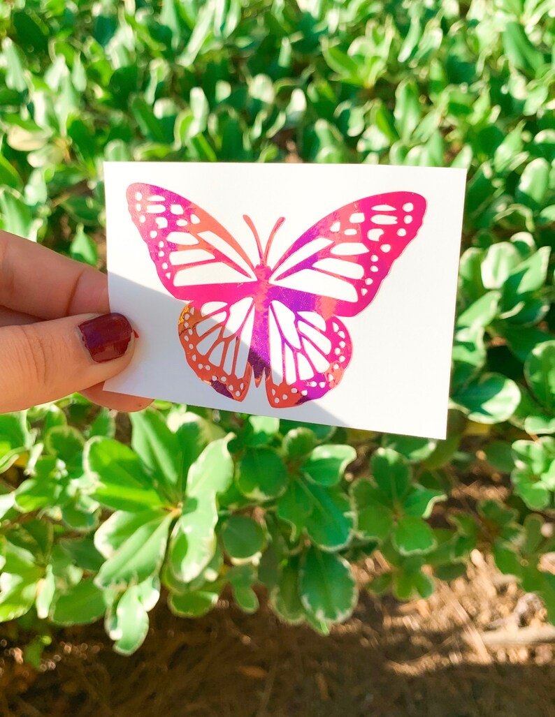 May include: A pink and purple butterfly sticker with white accents. The sticker is on a white background.