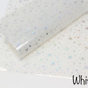 Pu&ograve; includere: Foglio di vinile bianco iridescente con un motivo ripetitivo di piccole stelle argentate. Il foglio &egrave; piegato a met&agrave;, mostrando il motivo su entrambi i lati. Il testo "White" &egrave; stampato in nero nella parte inferiore dell'immagine.