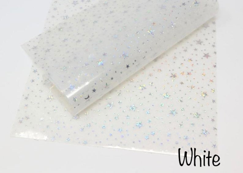 Pu&ograve; includere: Foglio di vinile bianco iridescente con un motivo ripetitivo di piccole stelle argentate. Il foglio &egrave; piegato a met&agrave;, mostrando il motivo su entrambi i lati. Il testo "White" &egrave; stampato in nero nella parte inferiore dell'immagine.
