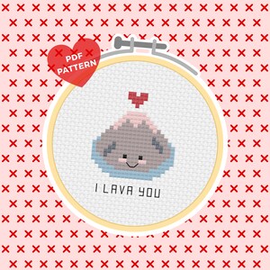 May include: A cross-stitch pattern featuring a cartoon volcano with a heart on top and the text "I LAVA YOU". The pattern is in a yellow embroidery hoop on a pink background with a red heart that says "PDF PATTERN".