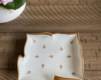 MCM vintage Arnart Creation white porcelain trinket dish or ash tray featuring a gold Fleur de Lis pattern and gold trim.