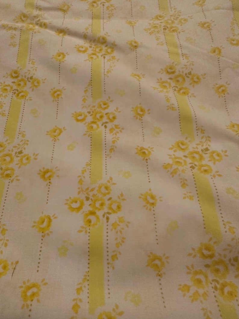May include: White fabric with a yellow floral pattern. The pattern features yellow roses and leaves on a white background with vertical yellow stripes.