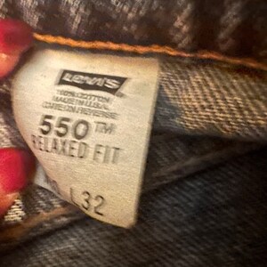 May include: A white Levi's tag with black text. The tag says "100% cotton made in USA care on reverse 550TM Relaxed Fit 32".