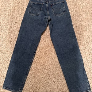 May include: A pair of blue denim jeans with a brown leather patch on the back waistband that says "Levi's" in white text.