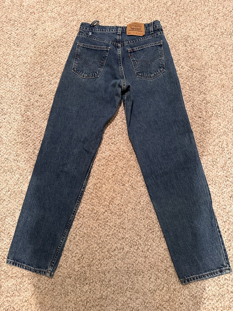May include: A pair of blue denim jeans with a brown leather patch on the back waistband that says "Levi's" in white text.