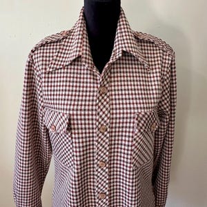 May include: A long-sleeved button-down shirt with a red and white checkered pattern. The shirt has two flap pockets on the chest and a pointed collar.