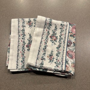 May include: Two white pillowcases with a floral pattern in shades of pink, green, and blue. The pattern features small flowers and vines.