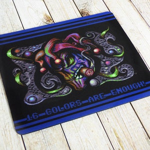 Könnte beinhalten: Schwarzes Mousepad mit einem farbenfrohen, pixeligen Narrendesign. Der Narr hat einen lila und roten Hut, grüne und blaue Akzente und ein grinsendes Gesicht. Der Text "16 COLORS ARE ENOUGH!" ist in Weiß gedruckt.
