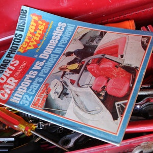 May include: A red toolbox filled with tools and a magazine titled "Sports Car Graphic" with the headline "Imports vs. Domestics 32 cars ranked in review!" and a photo of a red car.