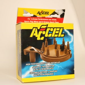 Puede incluir: Una caja amarilla y negra con un kit de tapa y rotor marrón para motores de alto rendimiento. La caja tiene el logotipo de ACCEL y el texto "High Performance Cap & Rotor Kit".