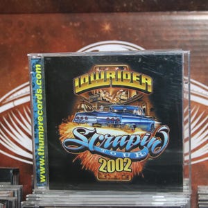 May include: A CD cover with a blue and white lowrider car on a black background. The text "Lowrider" and "Scrappin Tour 2002" is printed on the cover. The website "www.thumbpreocords.com" is printed on the side of the CD cover.