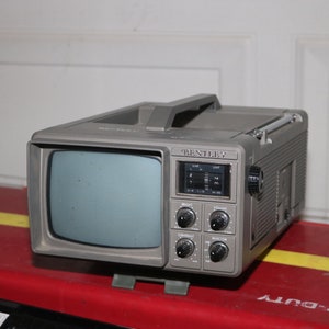 May include: A gray portable television with a black and white screen. The television has a built-in radio with a digital tuner and knobs for brightness, contrast, and volume. The television is labeled "Bentley".
