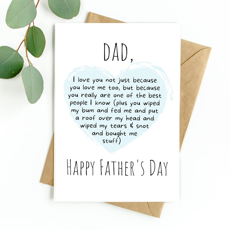 Pu&ograve; includere: Un biglietto per la festa del pap&agrave; con la parola "DAD," e un messaggio sincero a forma di cuore blu. Il biglietto &egrave; su sfondo bianco con una busta marrone e foglie di eucalipto.