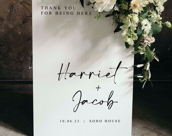 以下が含まれることがあります： 白い結婚式の看板に黒い文字が書かれています。看板には「来てくれてありがとう」「ハリエット＆ジェイコブ」「10.06.23 | SOHO HOUSE」と書いてあります。看板は白い花で飾られています。