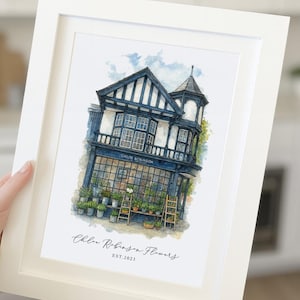May include: A framed watercolour illustration of a two-storey shop with dark blue timber framing and large windows. The storefront displays various potted plants on wooden stands. The text reads Chloe Robinson and Chloe Robinson Flowers EST.2023.