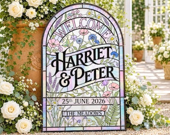 Op de afbeelding: Een boogvormig glas-in-lood bord met de tekst WELCOME, HARRIET & PETER, 25th JUNE 2026 en THE MEADOWS. Het ontwerp bevat florale illustraties van klaprozen, madeliefjes en lavendel op panelen van iriserend glas.