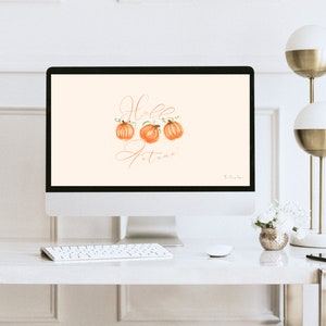 May include: A computer screen displaying a digital illustration of three orange pumpkins with green stems and leaves. The text "Hello Autumn" is written in cursive script on the screen.