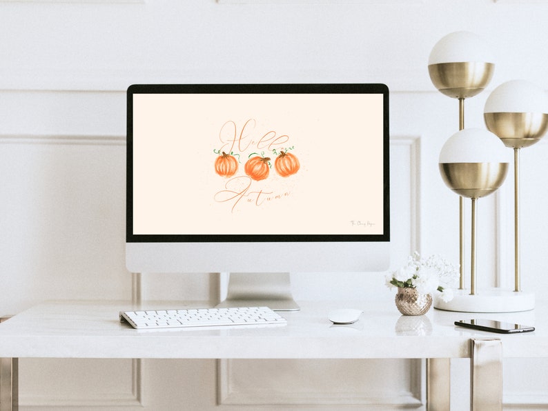 May include: A computer screen displaying a digital illustration of three orange pumpkins with green stems and leaves. The text "Hello Autumn" is written in cursive script on the screen.