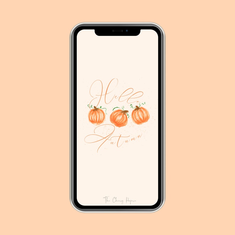 May include: A white phone screen with a digital illustration of three orange pumpkins with green stems and leaves. The text "Hello Autumn" is written in cursive script in brown. The text "The Cheery Paper" is at the bottom of the screen.