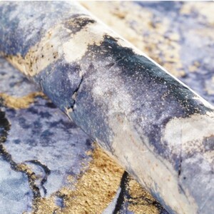 May include: Close-up of a blue and gold fabric with a marbled pattern. The fabric has a soft, velvety texture.