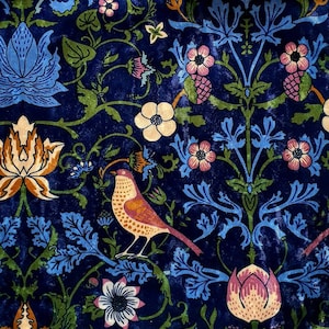 May include: A blue fabric with a repeating pattern of stylised flowers, leaves, and birds. The flowers are in shades of pink, white, and yellow. The birds are a light orange colour with brown spots.