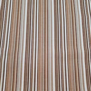 Peut inclure: Gros plan sur un tissu à rayures verticales dans les tons marron, beige et blanc. Les rayures sont de largeurs variables, créant un aspect texturé. Le tissu semble être une matière tissée.