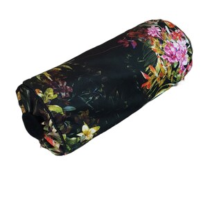 May include: A black cylindrical pillow with a floral print featuring pink, yellow, and green flowers on a dark background.