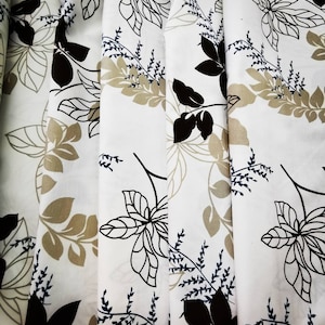 May include: White fabric with a repeating pattern of black and brown leaves. The fabric has a subtle sheen and a soft texture.