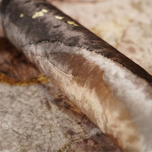 Op de afbeelding: Close-up van een bruine en beige stof met een subtiel patroon. De stof is zacht en textuurrijk, met een licht iriserende glans.