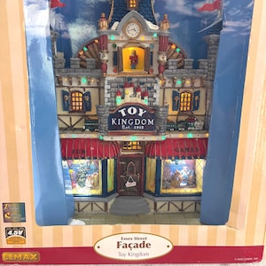May include: A detailed miniature of the Toy Kingdom storefront, featuring a clock tower and red awnings. The facade has the text "Toy Kingdom Est. 1912" and "Essex Street Façade". The windows display toys and the building is set against a blue sky backdrop.