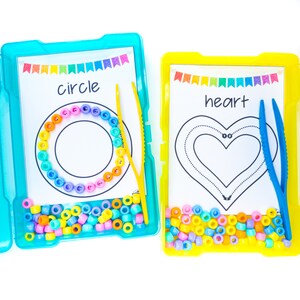 May include: Two colorful plastic containers with lids, each containing a sheet of paper with a shape outline and a set of colorful beads. One container has a circle outline and the word "circle" printed on the paper. The other container has a heart outline and the word "heart" printed on the paper. Both containers have a pair of tweezers.