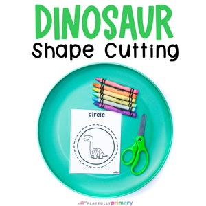 May include: A turquoise plate with a dinosaur shape cutting activity, a stack of crayons, and a pair of green scissors. The activity sheet says "circle" and has a dinosaur inside a circle.