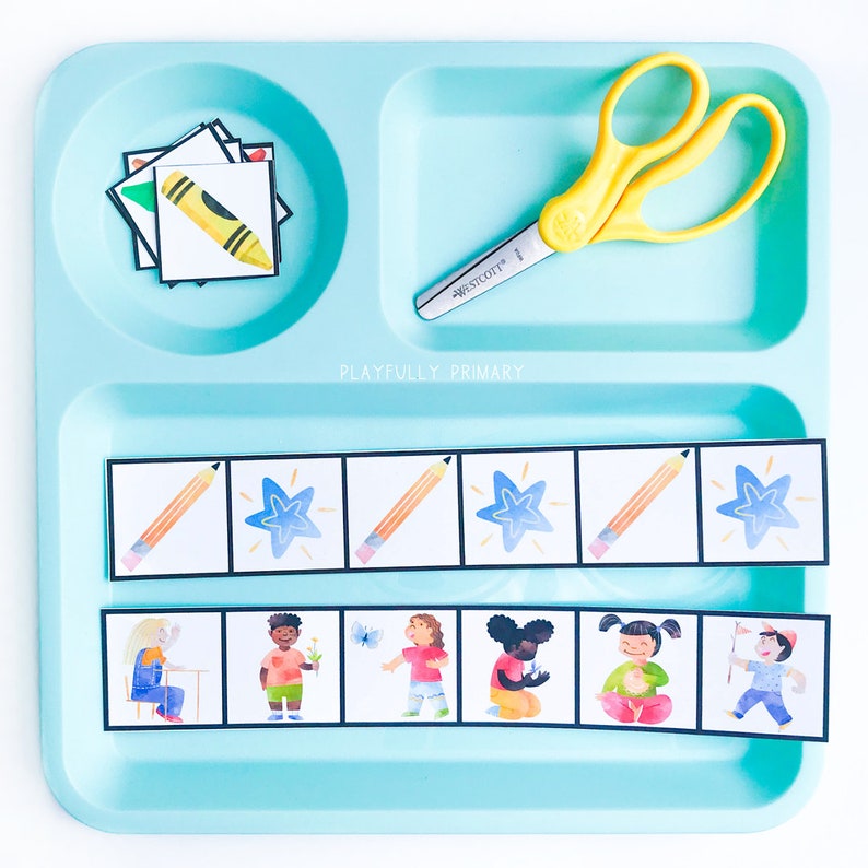 May include: A blue plastic tray with a set of colorful picture cards. The cards feature images of a pencil, a star, and children doing various activities. The tray also includes a pair of yellow scissors and a stack of cards with a crayon image.
