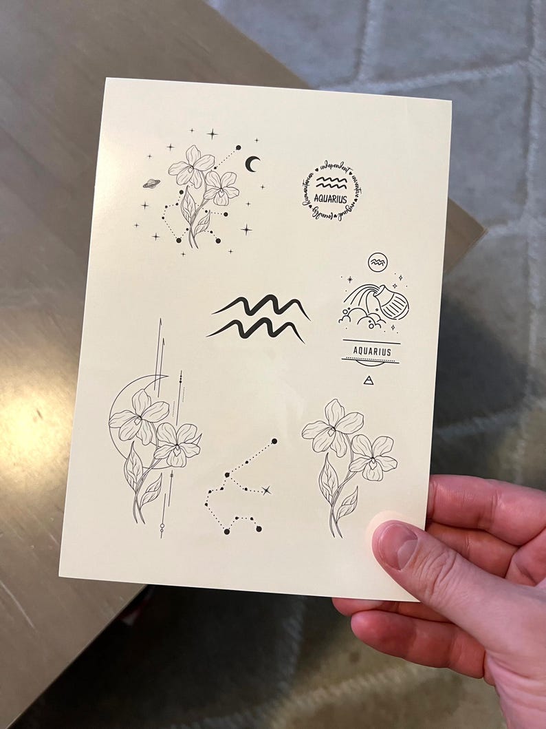 May include: A sheet of temporary tattoos featuring various Aquarius zodiac sign designs. The designs include a flower with a crescent moon, a wave, a water pitcher, a constellation, and a circle with the word "Aquarius" inside.