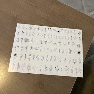 May include: A sheet of black and white floral and leaf illustrations. The sheet is divided into rows and columns, with each illustration separated by a small amount of space. The illustrations are simple and delicate, and they would be perfect for use in a variety of crafting projects.